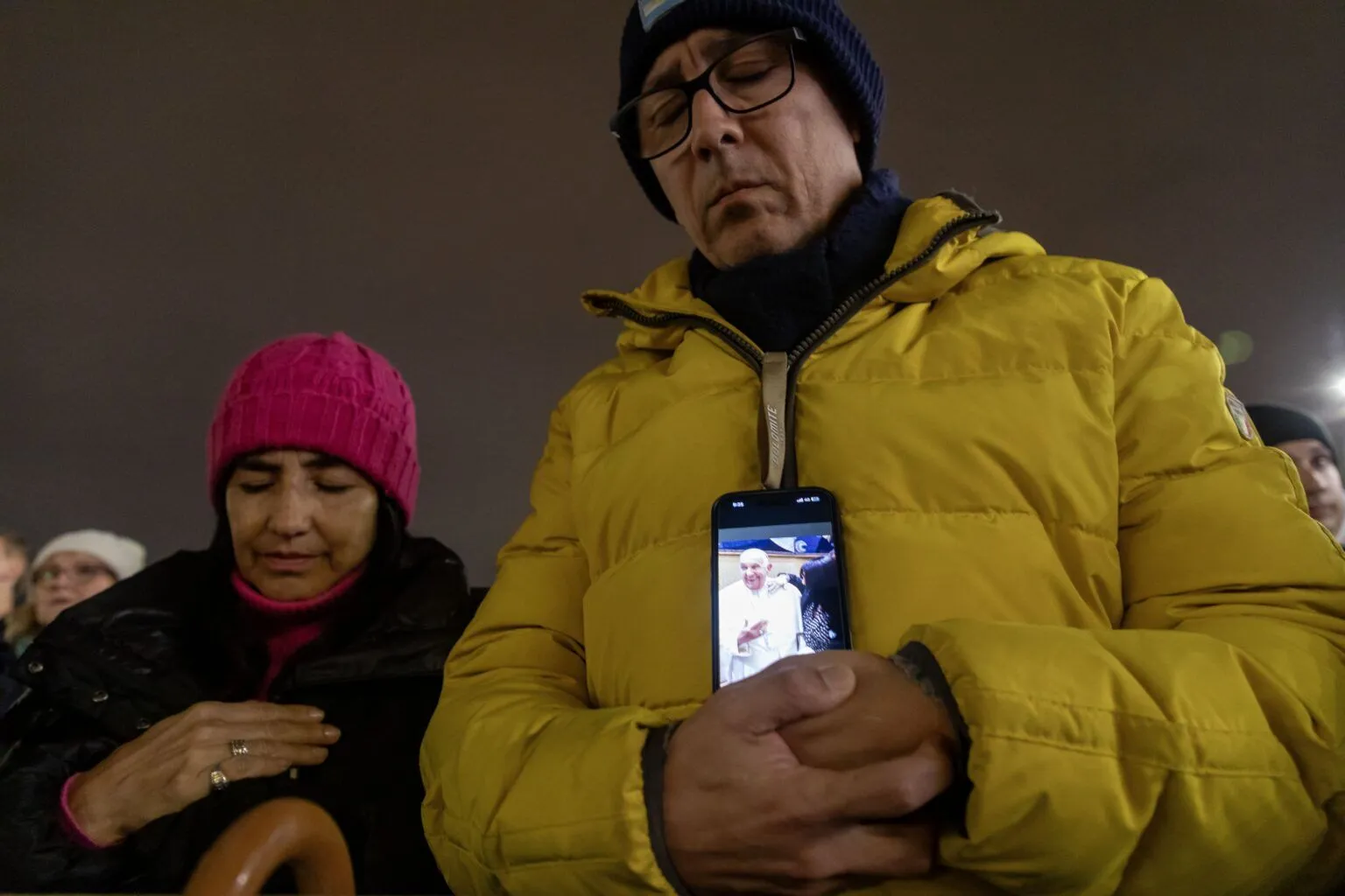 Un hombre sostiene su teléfono mostrando una imagen del Papa Francisco mientras se une al Cardenal Pietro Parolin, secretario de Estado del Vaticano, para recitar el rosario por el Papa en la Plaza de San Pedro en el Vaticano el 24 de febrero de 2025. Cardenales que viven en Roma, líderes de la Curia Romana y fieles se unieron a la oración nocturna. 